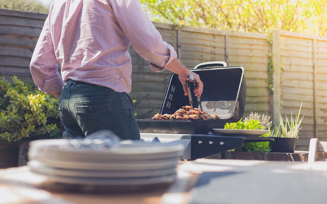 a man grilling meat in a backyard